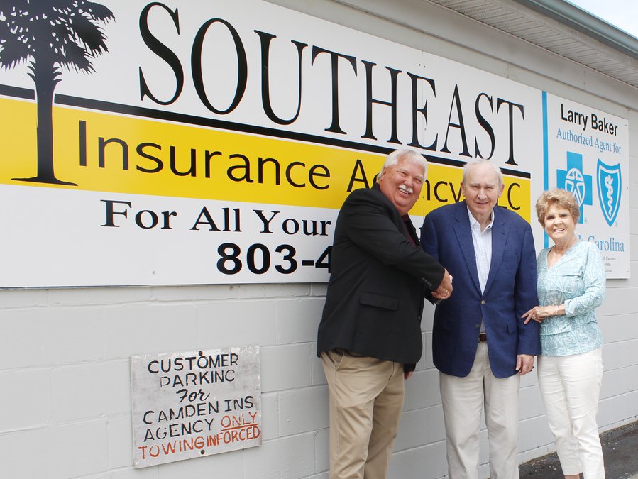 Larry Bakers is shaking hands with an elderly man standing beside a woman smiling.