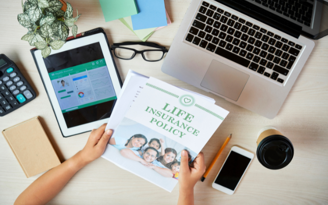An employee at their desk looking at a life insurance policy package.
